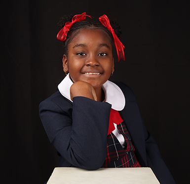 Elementary school girl with red ribbons smiling for the camera