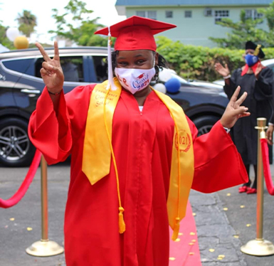 Female student in cap and gown doing a peace sign